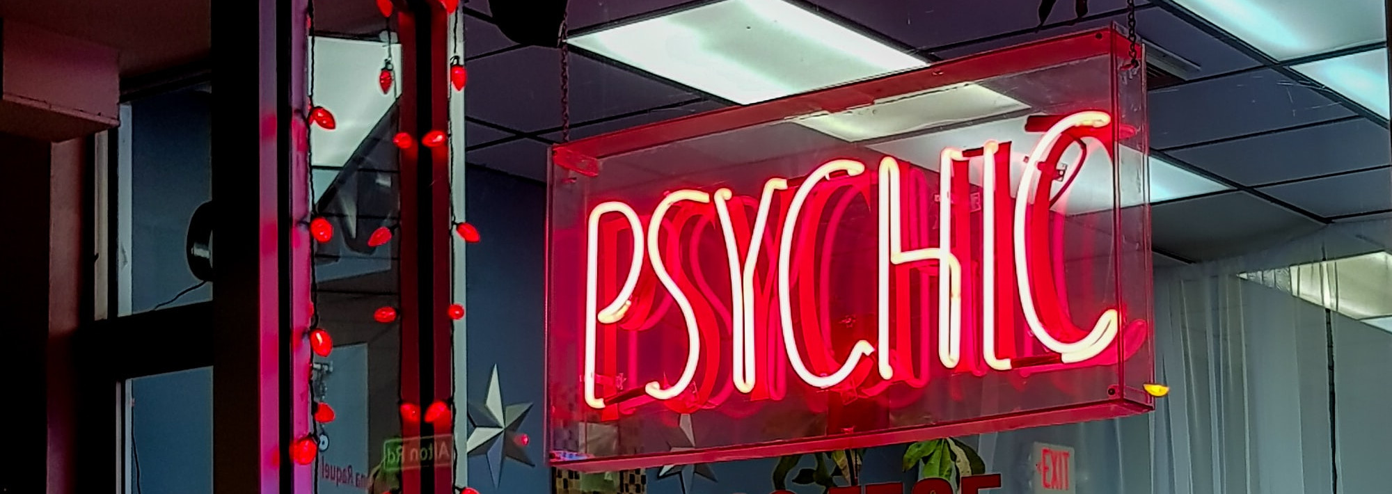 A red neon window sign with the word "Psychic"