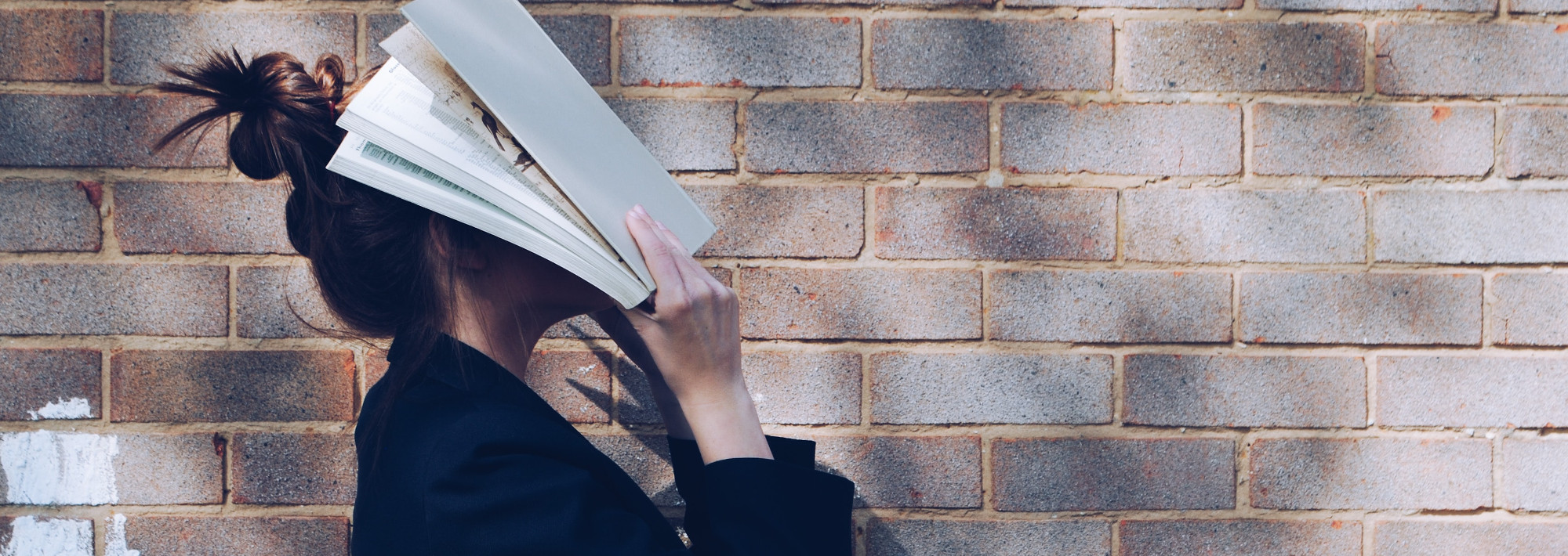 A student with a book covering their face out of frustration