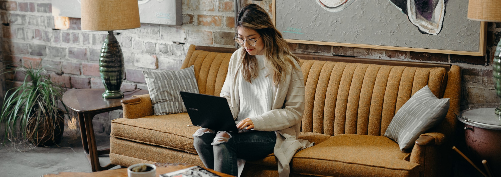 A woman sitting on a couch, working on a laptop