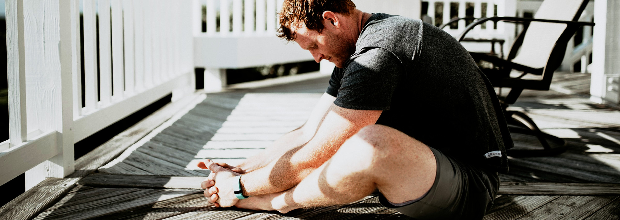 A man stretching by sitting and holding his feet in front of him.