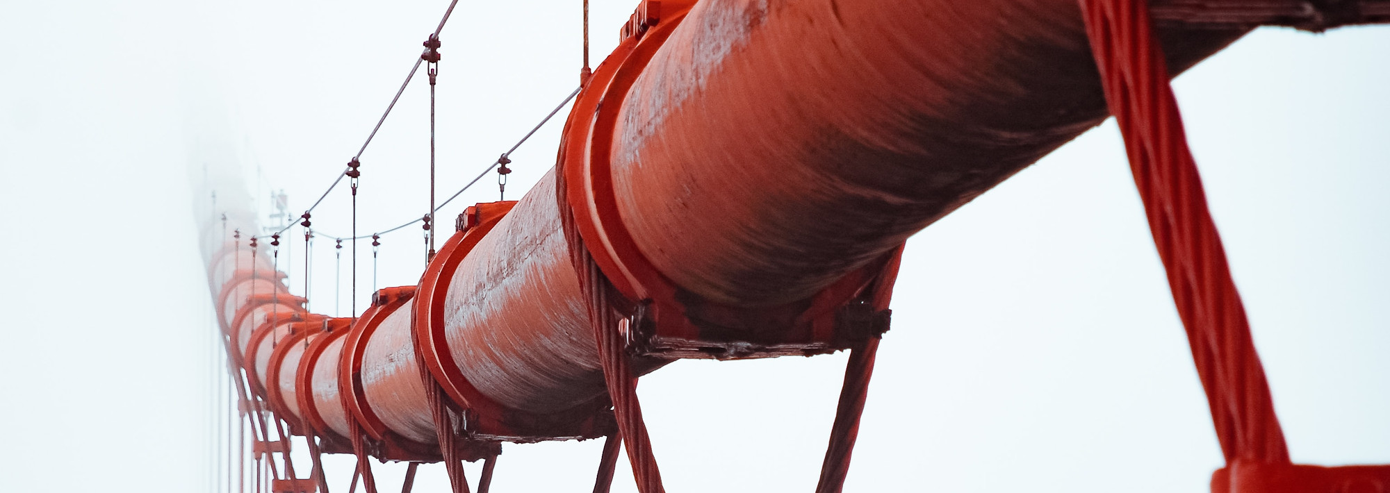 Part of the cabling on a suspension bridge disappearing into the clouds