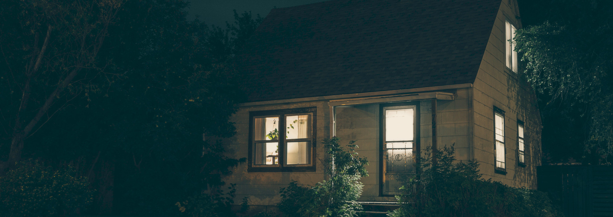 A house at night, with lights coming out of the windows.